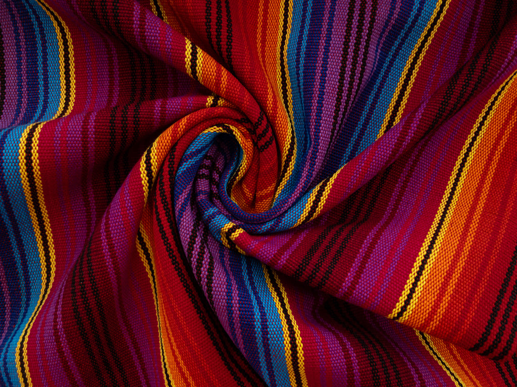A close-up of a woven textile with bold diagonal stripes in red, orange, yellow, blue, purple, and black, arranged in a spiral drape. Credit: Stonemountain & Daughter Fabrics.