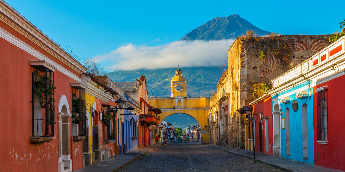 Colorful street scene with a clock tower and mountain in Antigua, Guatemala. Courtesy of Wikipedia. 